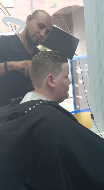 Ismaël aan het werk bij De Gouden Schaar, een klant aan het knippen